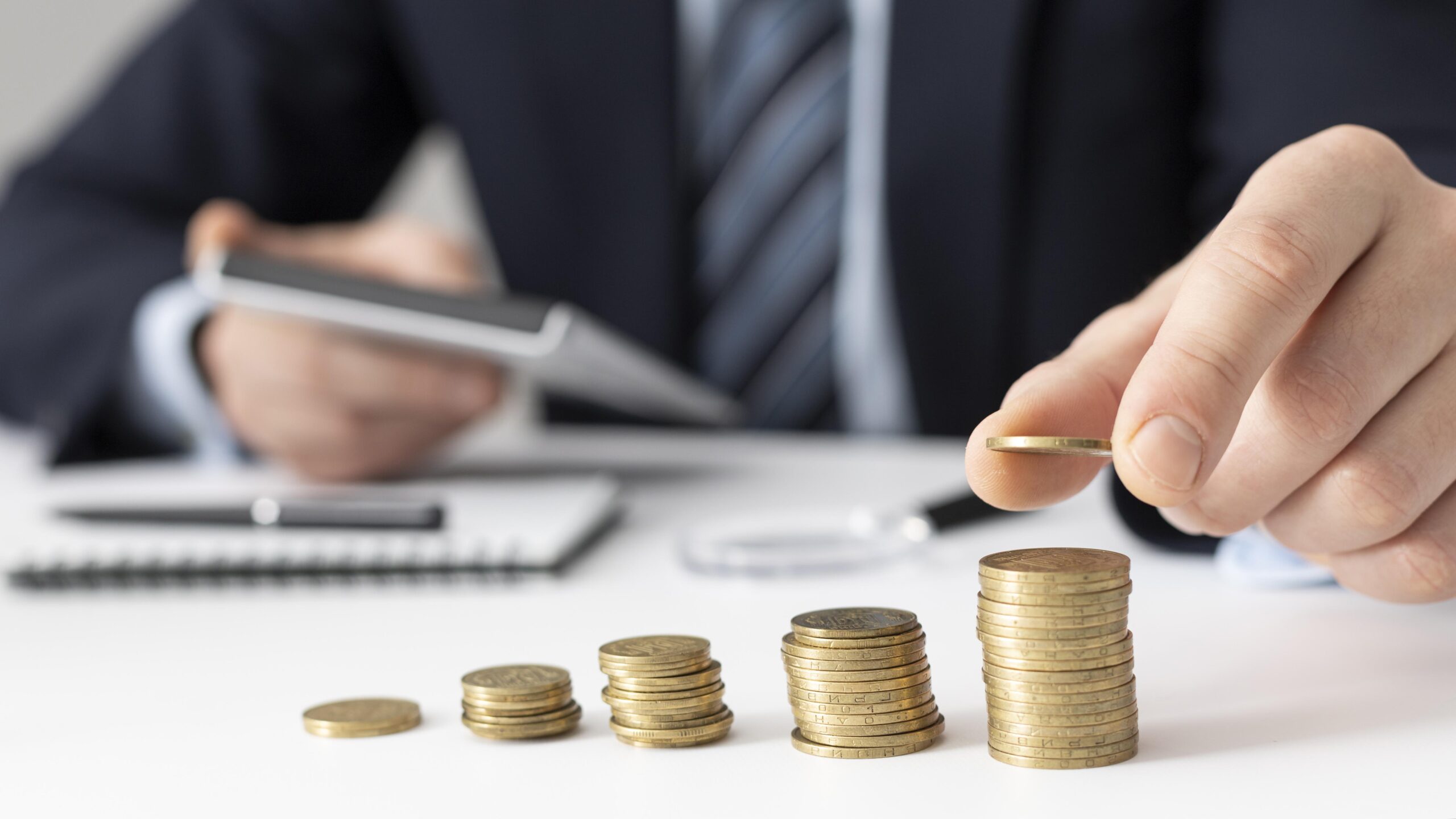 Businessman stacking coins and writing in a notebook about underinsurance